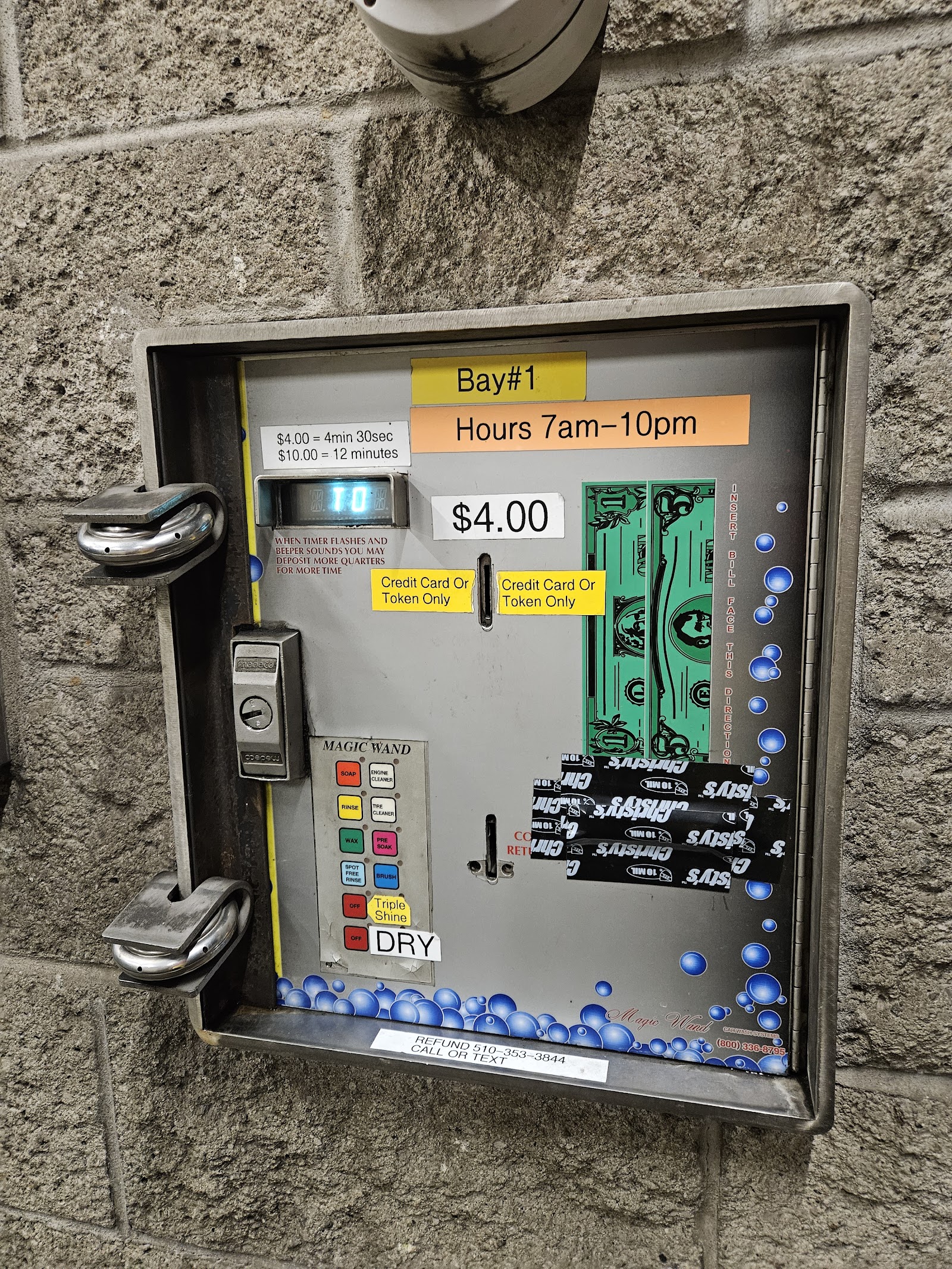 Close-up of a Clear Water Car Wash pay station: yellow Bay #1 sign, $4 sticker, magic wand selector with colored buttons for soap, foam, brush, rinse, wax, and dry